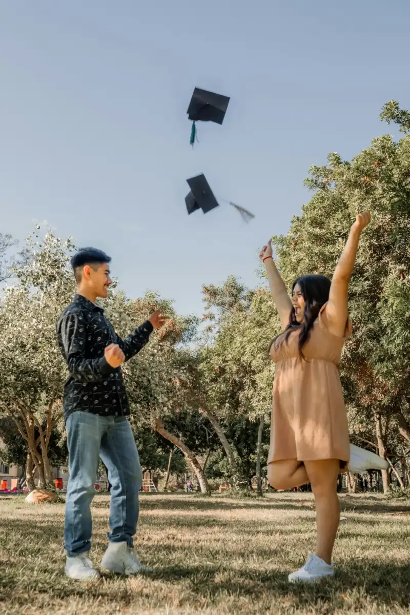 Two graduates throwing their caps into the air
